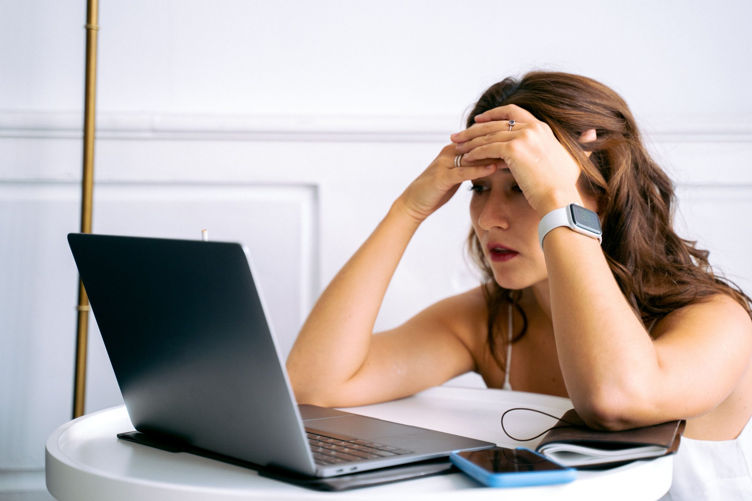 A woman looks at her laptop with exasperation